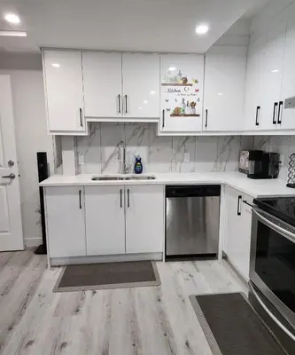 a kitchen with white cabinets and stainless steel appliances at 2 bedrooms luxury basement suite close to Calgary airport in Calgary