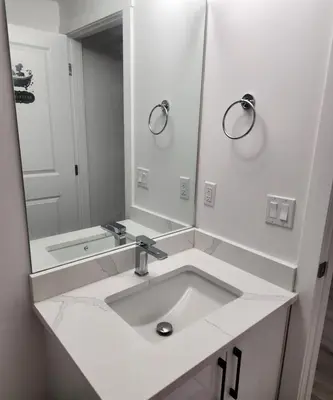 a white bathroom with a sink and a mirror at 2 bedrooms luxury basement suite close to Calgary airport in Calgary
