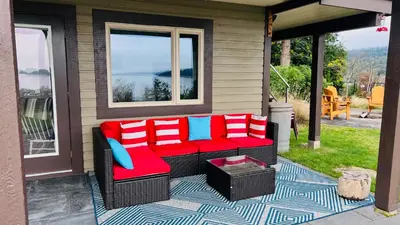 a porch with red and blue cushions on a patio at Oceanfront Garden Suite - Stunning Views & Wildlife in Halfmoon Bay
