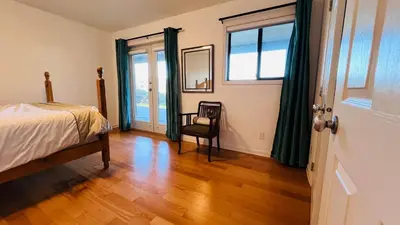 a bedroom with a bed and a chair and a window at Oceanfront Garden Suite - Stunning Views & Wildlife in Halfmoon Bay