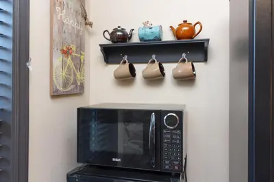 a microwave on a wall with a shelf and purses at Cole's Bay Vacation Retreat Library Room in YYJ
