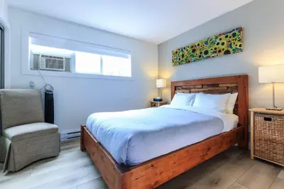 a bedroom with a bed and a chair and a window at Whistler Village North Retreat - Private Hot tub in Whistler