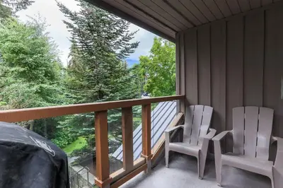 two white chairs sitting on a porch with a large window at Whistler Village North Retreat - Private Hot tub in Whistler