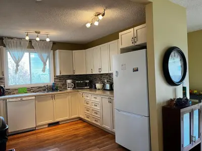 a kitchen with white cabinets and a white refrigerator at Biddington private room close airport! in Calgary