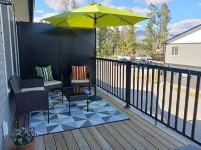 a patio with two chairs and an umbrella on a deck at 3 Bed Townhouse, Mountain Views, Large Deck, Air Con, Garage in Invermere
