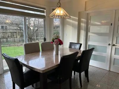 a dining room table with chairs and a vase of flowers at Spacious Bedroom with Two Queen Sized Bed in Richmond