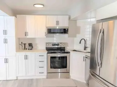 a kitchen with white cabinets and a stainless steel refrigerator at Private one Bedroom Suite for Rent in Calgary