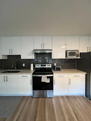 a kitchen with white cabinets and a black stove at Calm & Cozy Private Suite in Surrey