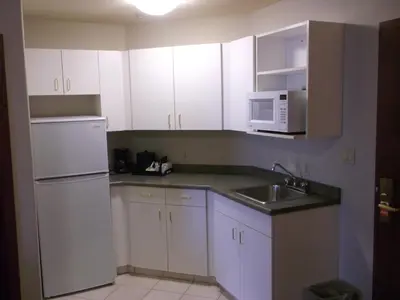 a kitchen with white cabinets and a sink and a microwave at Foxwood Inn and Suites in Fox Creek