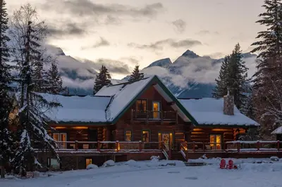 a log cabin in the snow with mountains in the background at Moberly Lodge in Golden