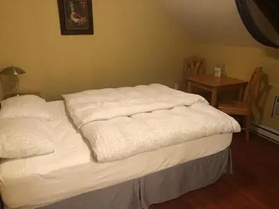 a bed with white blankets on it in a room at Crowsnest Vineyards Guesthouse in Keremeos