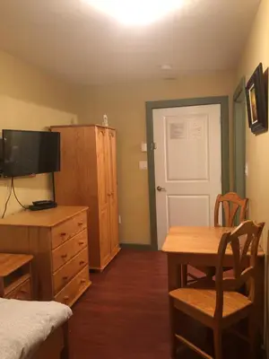 a bedroom with a bed and a desk with a television at Crowsnest Vineyards Guesthouse in Keremeos