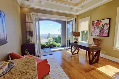 a living room with a desk and a sliding glass door at Stunning view in elegant 1 bedroom suite in West Vancouver