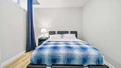 a bedroom with a bed with a blue and white blanket at Serene Stays in Calgary