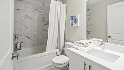 a white bathroom with a sink and a toilet and a tub at Serene Stays in Calgary