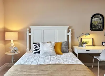 a bedroom with a bed with a white headboard and a desk at Entire Beautiful and Cozy Home in Edmonton