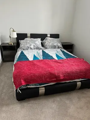 a bed with a red blanket on top of it at Modern & Stylish Private Suite in Pine Creek in Calgary