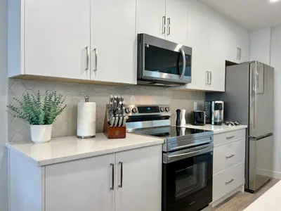 a kitchen with white cabinets and a stainless steel appliance at Mountain View New Luxury Condo at Banff Entrance in Canmore