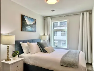 a bedroom with a large bed and a window at Mountain View New Luxury Condo at Banff Entrance in Canmore