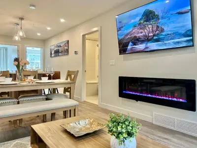 a living room with a fireplace and a tv on the wall at Mountain View New Luxury Condo at Banff Entrance in Canmore