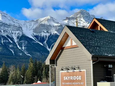 a ski lodge with a snow covered mountain in the background at Mountain View New Luxury Condo at Banff Entrance in Canmore