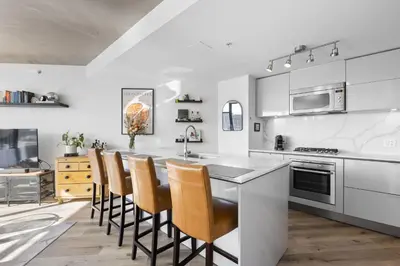a kitchen with white cabinets and a kitchen island with chairs at Luxury Central Apartment with City Views in Vancouver