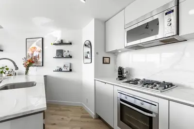 a white kitchen with a stove and a sink at Luxury Central Apartment with City Views in Vancouver