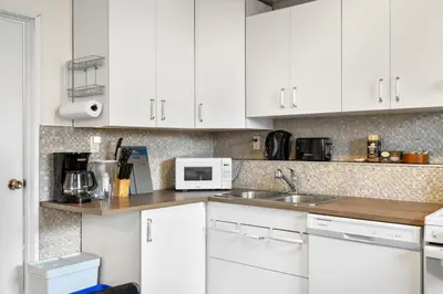 a kitchen with white cabinets and a sink at 1 Bedroom Cozy Retreat - Queen Bed, Pet Friendly, Smart TV, Secure & Private Access, Free Parking, Netflix & More! in Calgary