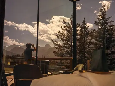 a person taking a picture of a mountain view from a hotel room at Skyridge Glamping in Kananaskis Village