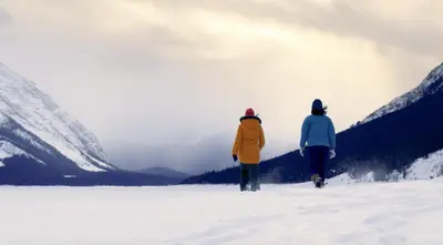 two people walking in the snow in the mountains at Skyridge Glamping in Kananaskis Village