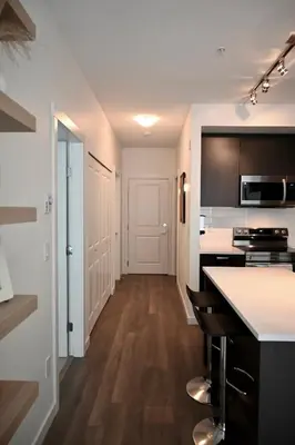 a kitchen with white walls and wooden floors at Stylish 2-Bedroom Condo - Premium Comfort, Central Location in Surrey