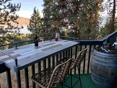 a wooden table with two glasses of wine on a deck at Desert Pines Holiday Getaway in Peachland
