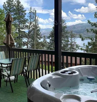 a bath tub on a porch with a table and chairs at Desert Pines Holiday Getaway in Peachland