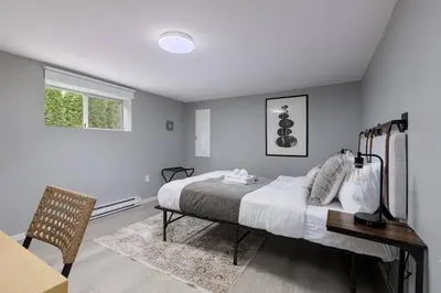 a bedroom with a bed and a desk and a window at Spacious 4BR Retreat near YVR and DT in Vancouver