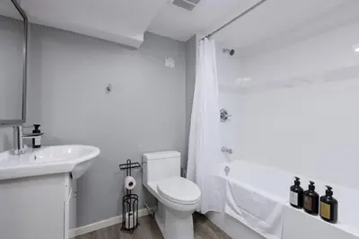 a white bathroom with a toilet and a sink at Spacious 4BR Retreat near YVR and DT in Vancouver