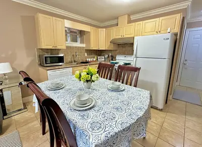 a kitchen with a table with chairs and a white refrigerator at Lovely 2BR BSMT Suite w Parking for Pickup in North Vancouver