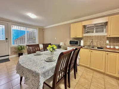 a kitchen and dining room with a table and chairs at Lovely 2BR BSMT Suite w Parking for Pickup in North Vancouver