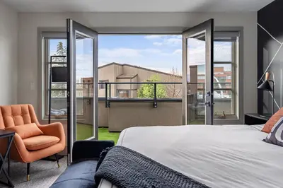 a bedroom with a bed and a chair and windows at Rare Find, Double King Beds, Cozy and Vibrant in Calgary