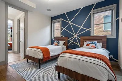 two beds in a bedroom with a blue wall at Rare Find, Double King Beds, Cozy and Vibrant in Calgary