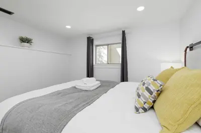 a white bedroom with a bed with two towels on it at Cozy BSMT suite Near UBC, Kits, and DT Vancouver in Vancouver