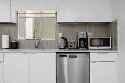 a white kitchen with white cabinets and appliances at Cozy BSMT suite Near UBC, Kits, and DT Vancouver in Vancouver