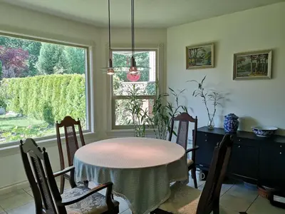 a dining room with a table and chairs and a window at Meadow Ridge Haven in Maple Ridge District Municipality