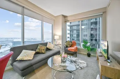 a living room with a couch and a glass table at The Urban Peak on the 19th Floor of the Alura in Calgary