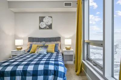 a bedroom with a bed and a large window at The Urban Peak on the 19th Floor of the Alura in Calgary