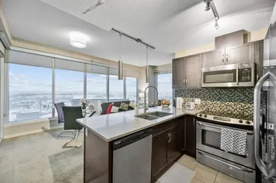 a kitchen with stainless steel appliances and glass windows at The Urban Peak on the 19th Floor of the Alura in Calgary