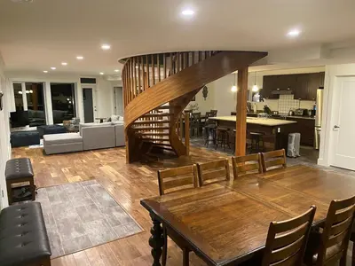 a living room with a wooden table and a spiral staircase at Bluesky Lodge in Golden