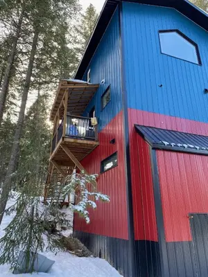 a red and blue building with a deck in the snow at Birch Suite in Golden