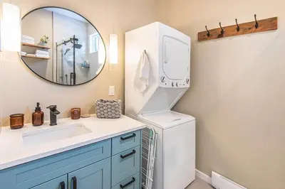 a bathroom with a sink and a white refrigerator at Sparkling NEW Rossland Midtown Studio Apartment in Rossland