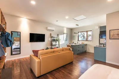 a living room with a couch and a kitchen at Sparkling NEW Rossland Midtown Studio Apartment in Rossland
