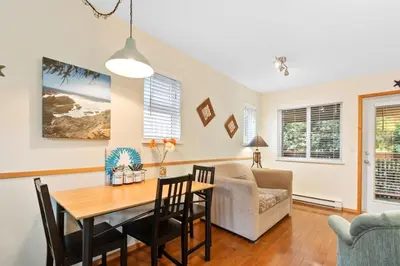 a living room with a table and a couch at Tyee Retreat Cozy Lofted 1 Bedroom Cabin in Ucluelet